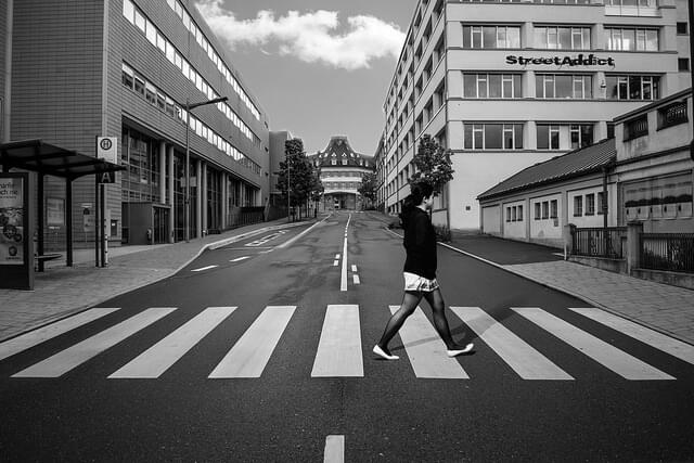 Ein Schwarzweißfoto einer Person, die an einem Zebrastreifen eine Straße überquert